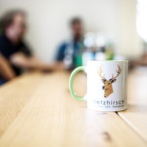 Eine Netzhirsch-Kaffee-Tasse steht auf dem Tisch